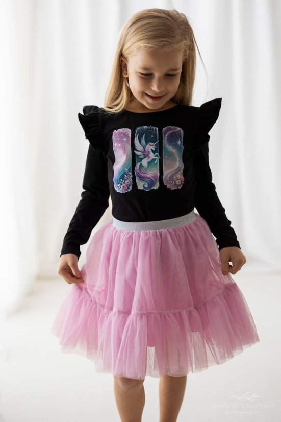 Malá dívka v černé blůzce s potiskem jednorožce a růžové tylové sukni. Stylový a pohodlný outfit pro každou malou princeznu.