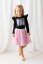 Malá dívka v černé blůzce s potiskem jednorožce a růžové tylové sukni. Stylový a pohodlný outfit pro každou malou princeznu.