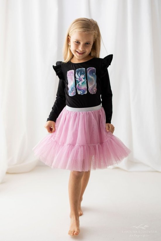 Malá dívka v černé blůzce s potiskem jednorožce a růžové tylové sukni. Stylový a pohodlný outfit pro každou malou princeznu.